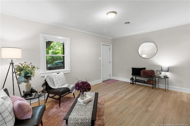 living area with light wood-type flooring and crown molding