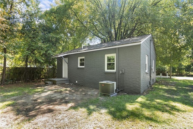 view of side of home with central AC and a yard