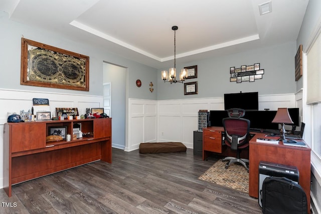 office featuring a raised ceiling, dark wood-type flooring, and an inviting chandelier