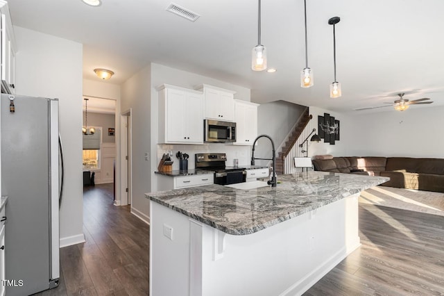 kitchen featuring white cabinetry, hanging light fixtures, a center island with sink, and appliances with stainless steel finishes