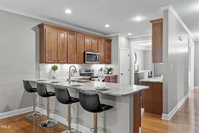 kitchen with light stone counters, stainless steel appliances, kitchen peninsula, and sink