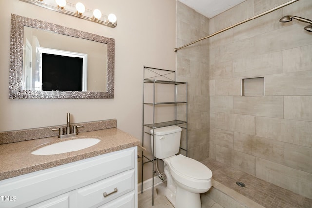 bathroom with vanity, toilet, and tiled shower