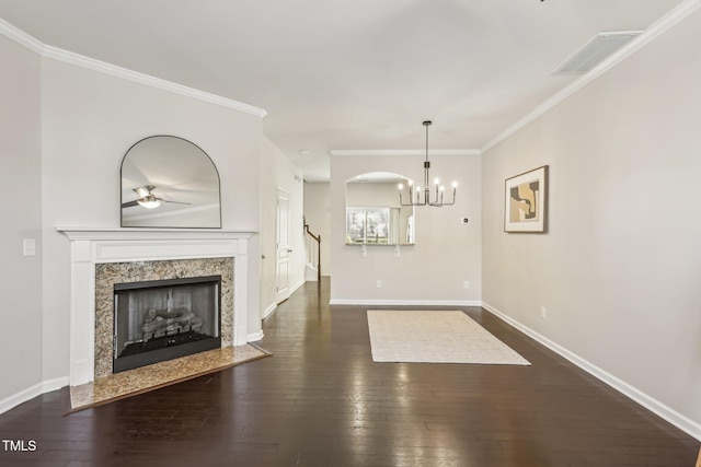 unfurnished living room with crown molding, dark wood-type flooring, a notable chandelier, and a high end fireplace