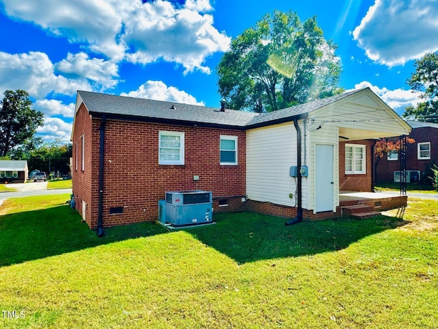 back of property with a yard and central AC