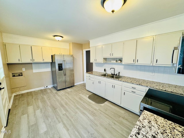 kitchen featuring sink, light stone counters, light hardwood / wood-style floors, and appliances with stainless steel finishes