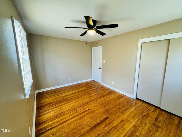 unfurnished bedroom featuring ceiling fan, multiple windows, and wood-type flooring