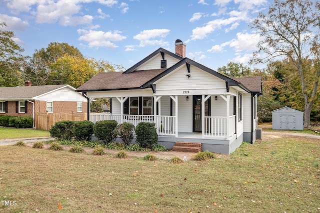 bungalow-style house with a storage unit, cooling unit, a porch, and a front lawn