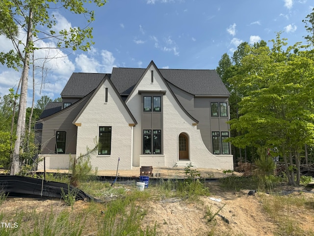 view of front of house with brick siding and roof with shingles