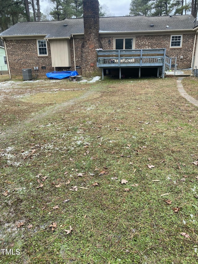 rear view of property with a wooden deck, central AC unit, and a lawn