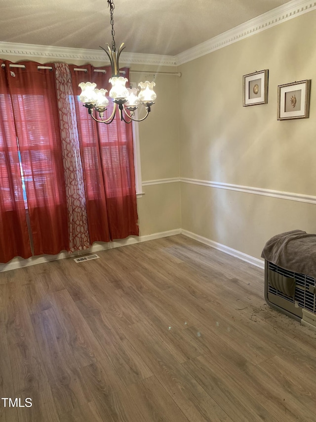 unfurnished dining area with crown molding, wood-type flooring, and a chandelier