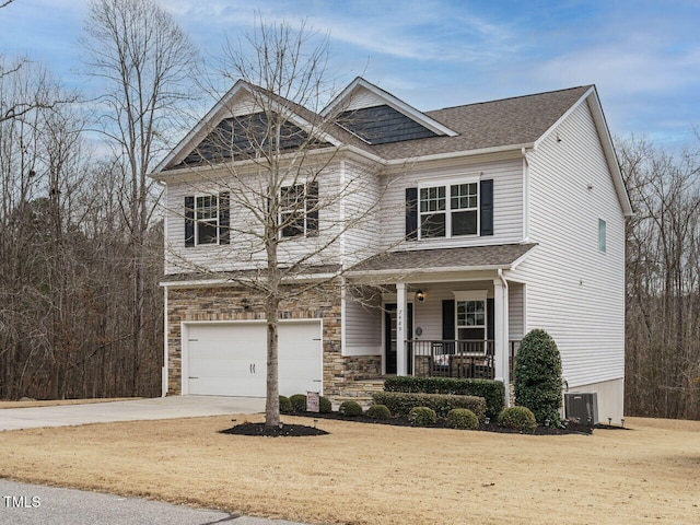 craftsman-style house featuring a garage, covered porch, central AC, and a front yard