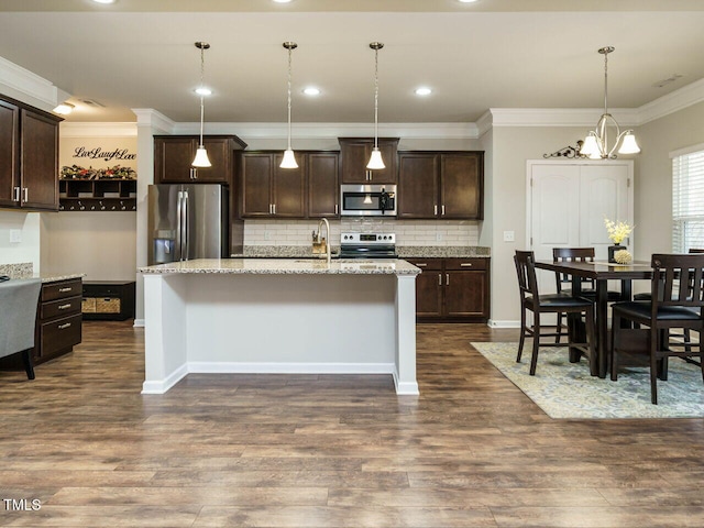 kitchen with dark brown cabinetry, pendant lighting, an island with sink, stainless steel appliances, and dark hardwood / wood-style floors