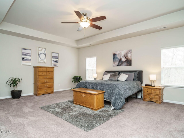 bedroom featuring ceiling fan, a raised ceiling, and light carpet