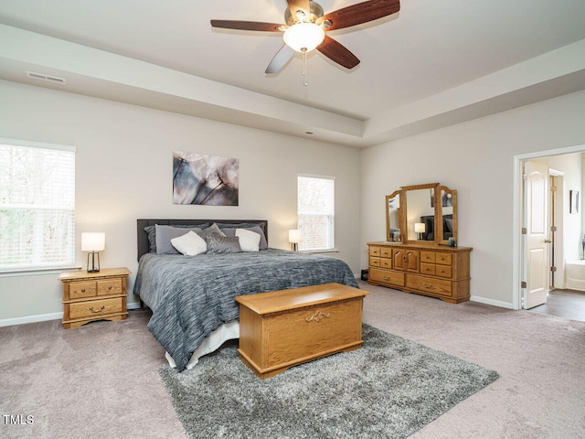 bedroom with ceiling fan, carpet floors, and a tray ceiling