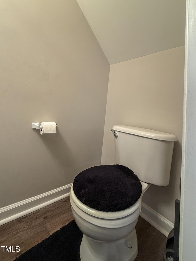 bathroom featuring wood-type flooring, toilet, and vaulted ceiling