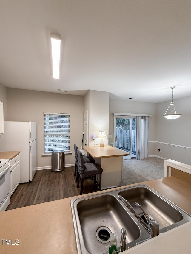 kitchen with pendant lighting, sink, white appliances, plenty of natural light, and white cabinets