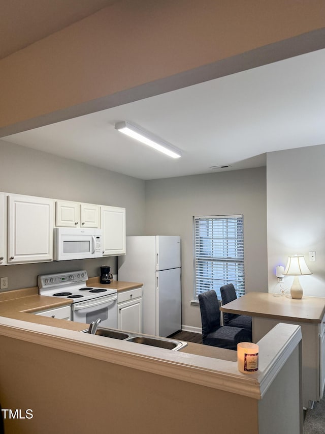 kitchen featuring white appliances, kitchen peninsula, and white cabinets