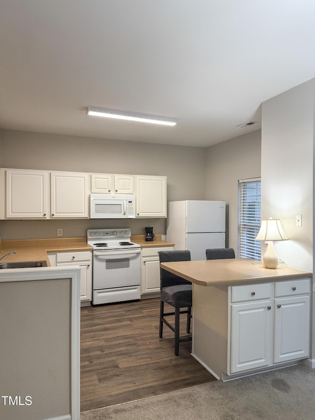 kitchen featuring sink, white appliances, white cabinetry, a kitchen breakfast bar, and dark hardwood / wood-style flooring