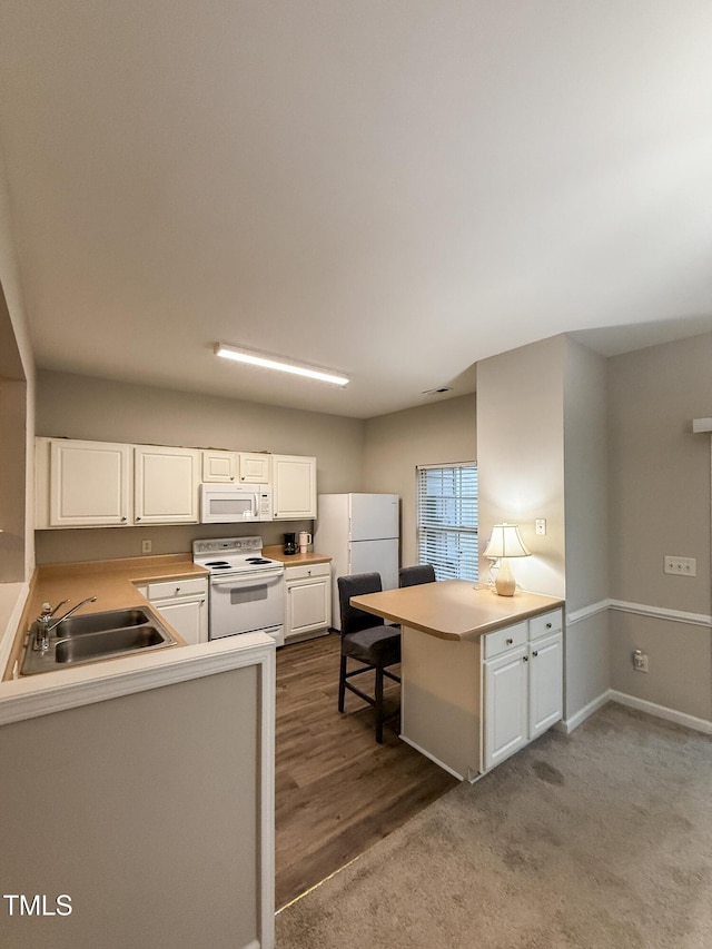 kitchen with white appliances, kitchen peninsula, sink, and white cabinets