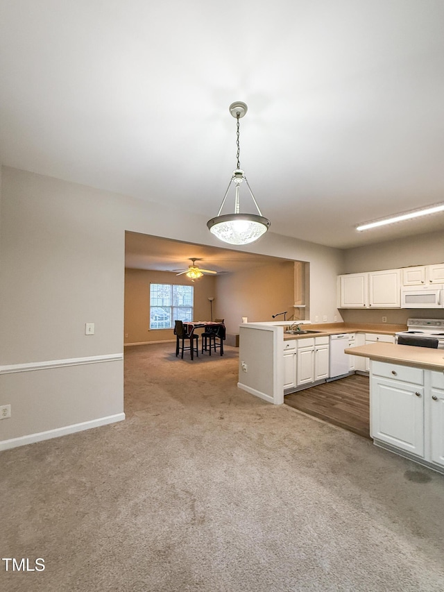 kitchen with pendant lighting, sink, white appliances, white cabinets, and light carpet