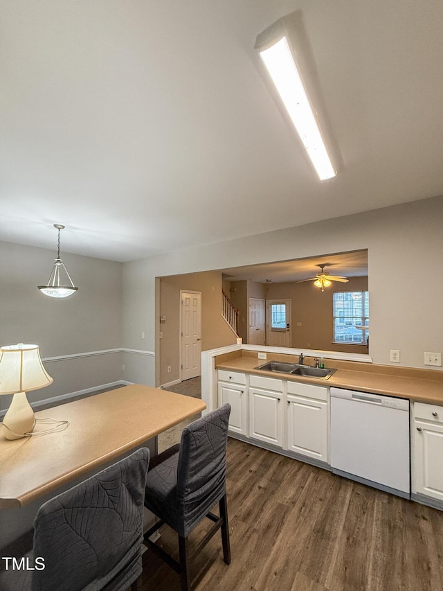 kitchen featuring white dishwasher, decorative light fixtures, sink, and white cabinets