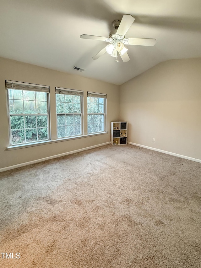 carpeted empty room featuring lofted ceiling, a healthy amount of sunlight, and ceiling fan