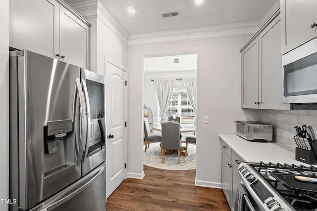 kitchen featuring gray cabinetry, backsplash, stainless steel appliances, crown molding, and dark wood-type flooring