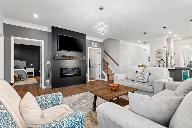 living room featuring an inviting chandelier, a fireplace, crown molding, and dark wood-type flooring