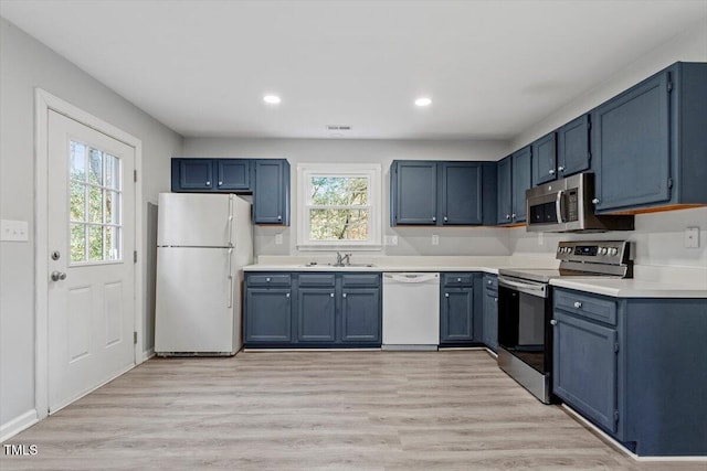 kitchen with stainless steel appliances, blue cabinets, sink, and light wood-type flooring