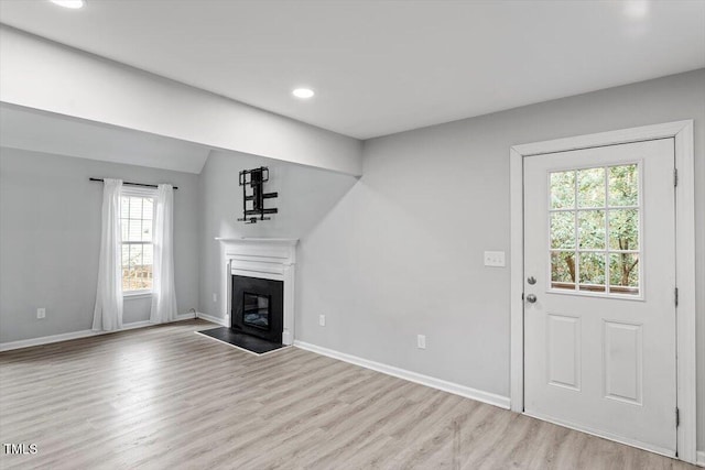 unfurnished living room featuring vaulted ceiling and light hardwood / wood-style floors