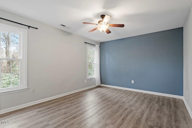 empty room with ceiling fan, light hardwood / wood-style floors, and a healthy amount of sunlight