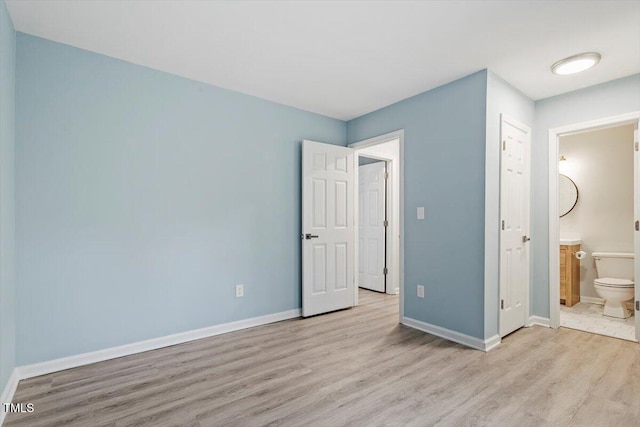 unfurnished bedroom featuring ensuite bath and light wood-type flooring