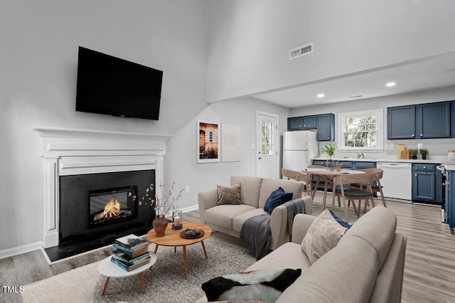 living room with sink, light hardwood / wood-style flooring, and a high ceiling