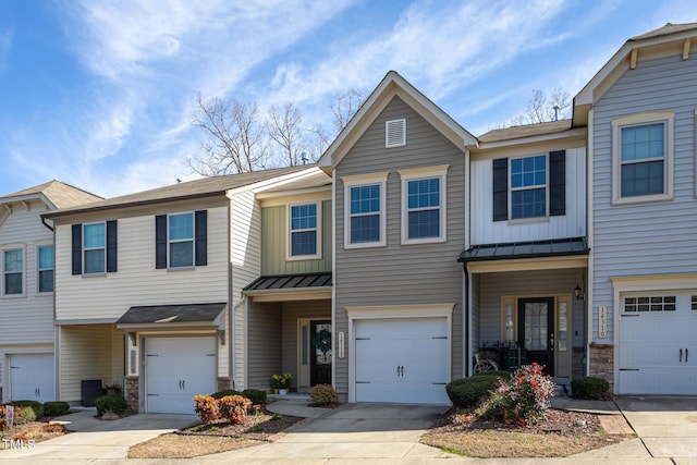 multi unit property with stone siding, a standing seam roof, an attached garage, and concrete driveway