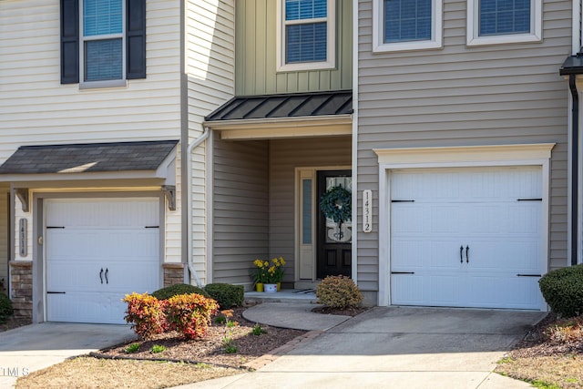 doorway to property featuring board and batten siding, a standing seam roof, driveway, and an attached garage