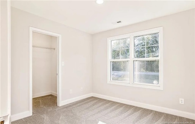 unfurnished bedroom featuring a spacious closet, a closet, and carpet floors