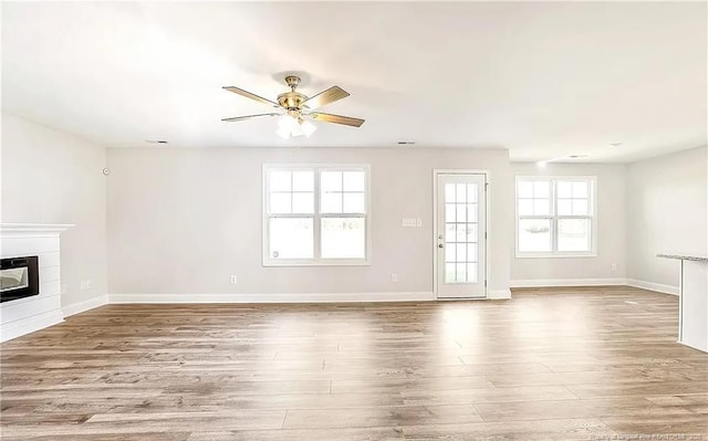 unfurnished living room with light wood-type flooring, heating unit, and ceiling fan