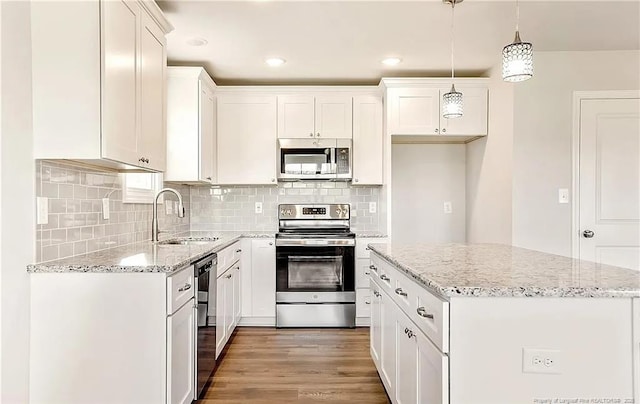 kitchen featuring hanging light fixtures, sink, white cabinets, a kitchen island, and stainless steel appliances