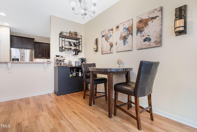 dining area with light hardwood / wood-style flooring and an inviting chandelier