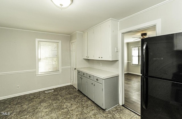 kitchen with white cabinetry, black fridge, and ornamental molding