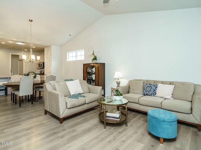 living room with ceiling fan with notable chandelier, light hardwood / wood-style flooring, and lofted ceiling