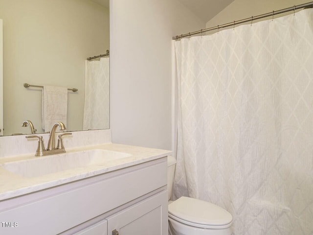 bathroom with toilet, vanity, and lofted ceiling