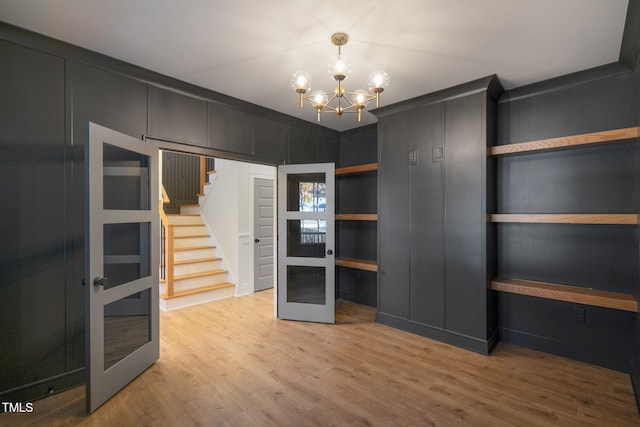 spacious closet featuring wood-type flooring, a notable chandelier, and french doors