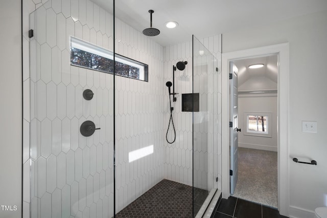 bathroom featuring tile patterned flooring, vaulted ceiling, and tiled shower