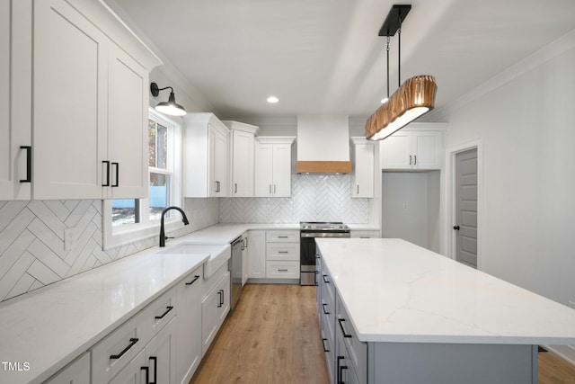 kitchen featuring stainless steel appliances, custom range hood, white cabinets, and a kitchen island