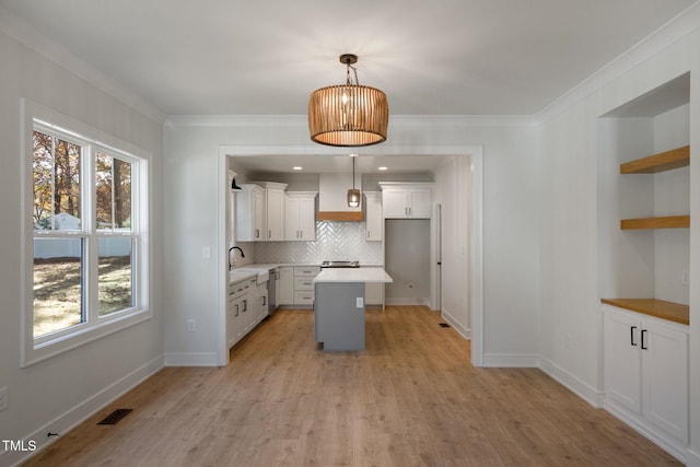 kitchen with a kitchen island, pendant lighting, white cabinets, decorative backsplash, and light hardwood / wood-style flooring