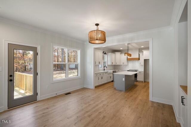 kitchen featuring stove, hanging light fixtures, tasteful backsplash, white cabinets, and a kitchen island