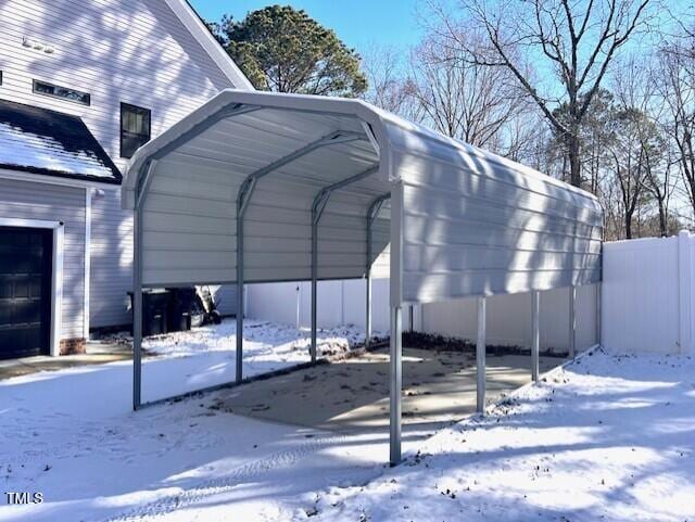 snow covered parking area with a carport