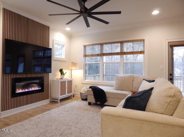 living room with crown molding, ceiling fan, light hardwood / wood-style flooring, and a wealth of natural light