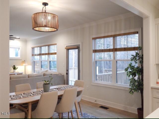 dining area with ornamental molding and light hardwood / wood-style floors